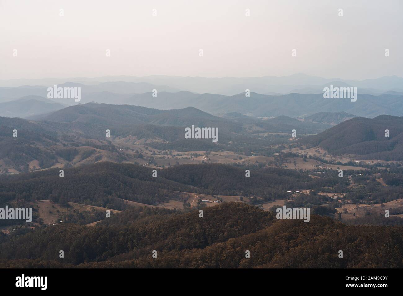 Mirando hacia el valle, en la pequeña ciudad pequeña de Byabarra, Nueva Gales del Sur con brumosas montañas en la distancia. Tomada desde el Monte Comboyne. Foto de stock