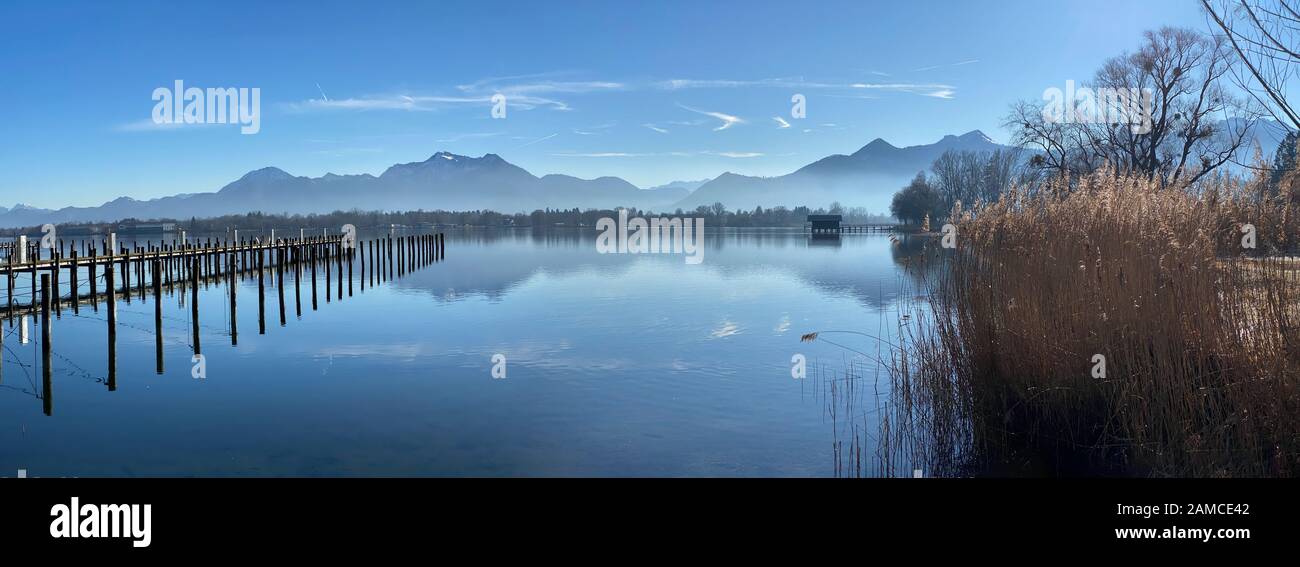 Día brumoso en el lago Chiemsee en Baviera - cabaña y montañas reflejando en el agua Foto de stock