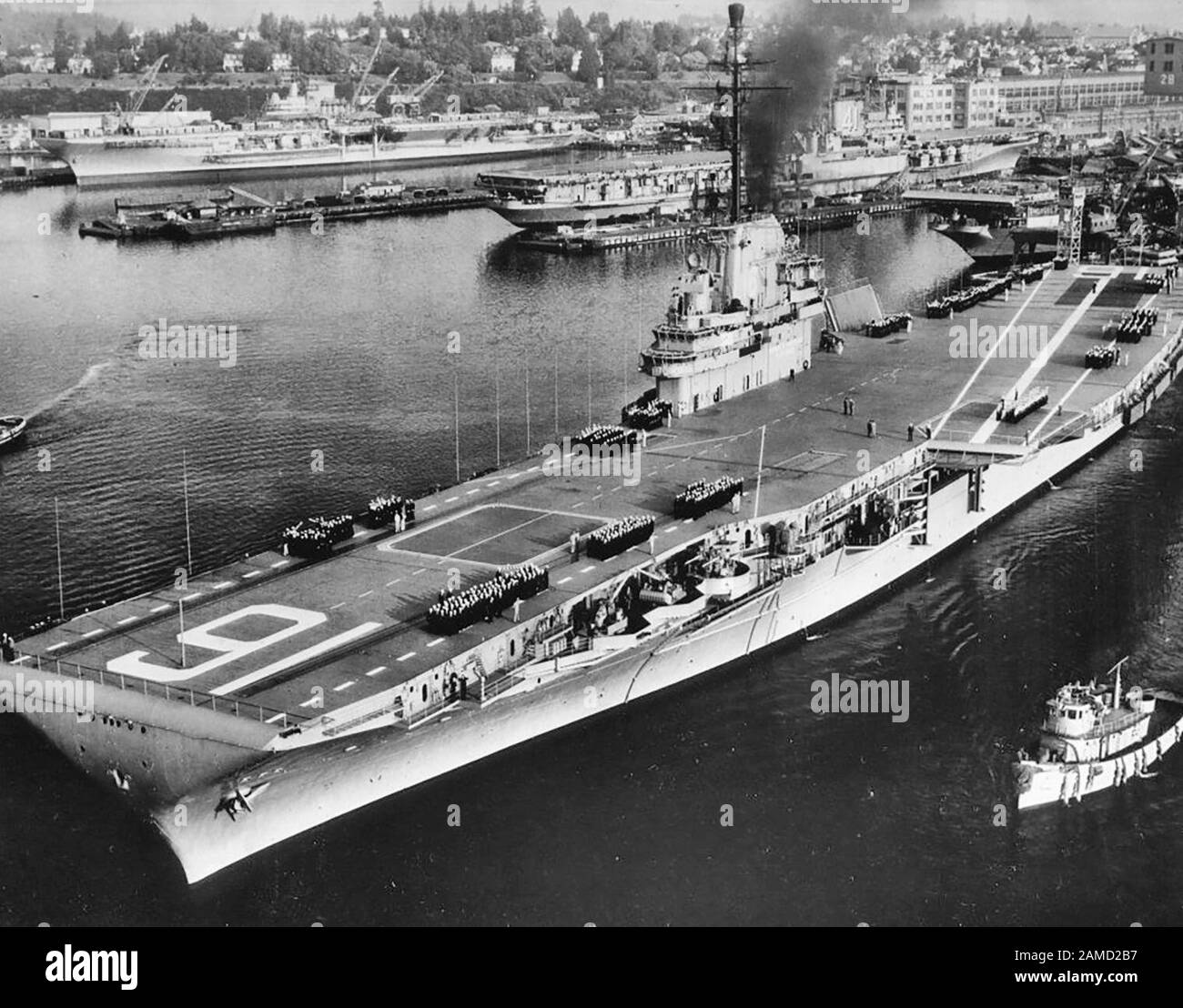 El portaaviones USS Lexington (CVA-16) de la Marina de los EE.UU. Sale del astillero naval Puget Sound, Washington (EE.UU.), en septiembre de 1955, se dirigió a sus ensayos iniciales sobre el mar después de las conversiones SCB-27C y -125. El USS Franklin D. Roosevelt (CVA-42), en el fondo, está bien en su modernización SCB-110. USS Midway (CVA-41), en la distancia media, está en las etapas muy tempranas de (o siendo preparado para) su propio SCB-110. Otro portador de la clase Essex es visible a la derecha, ya sea USS Essex (CVA-9) o USS Yorktown (CVA-10) durante sus conversiones SCB-125. Alrededor De Septiembre De 1955 Foto de stock