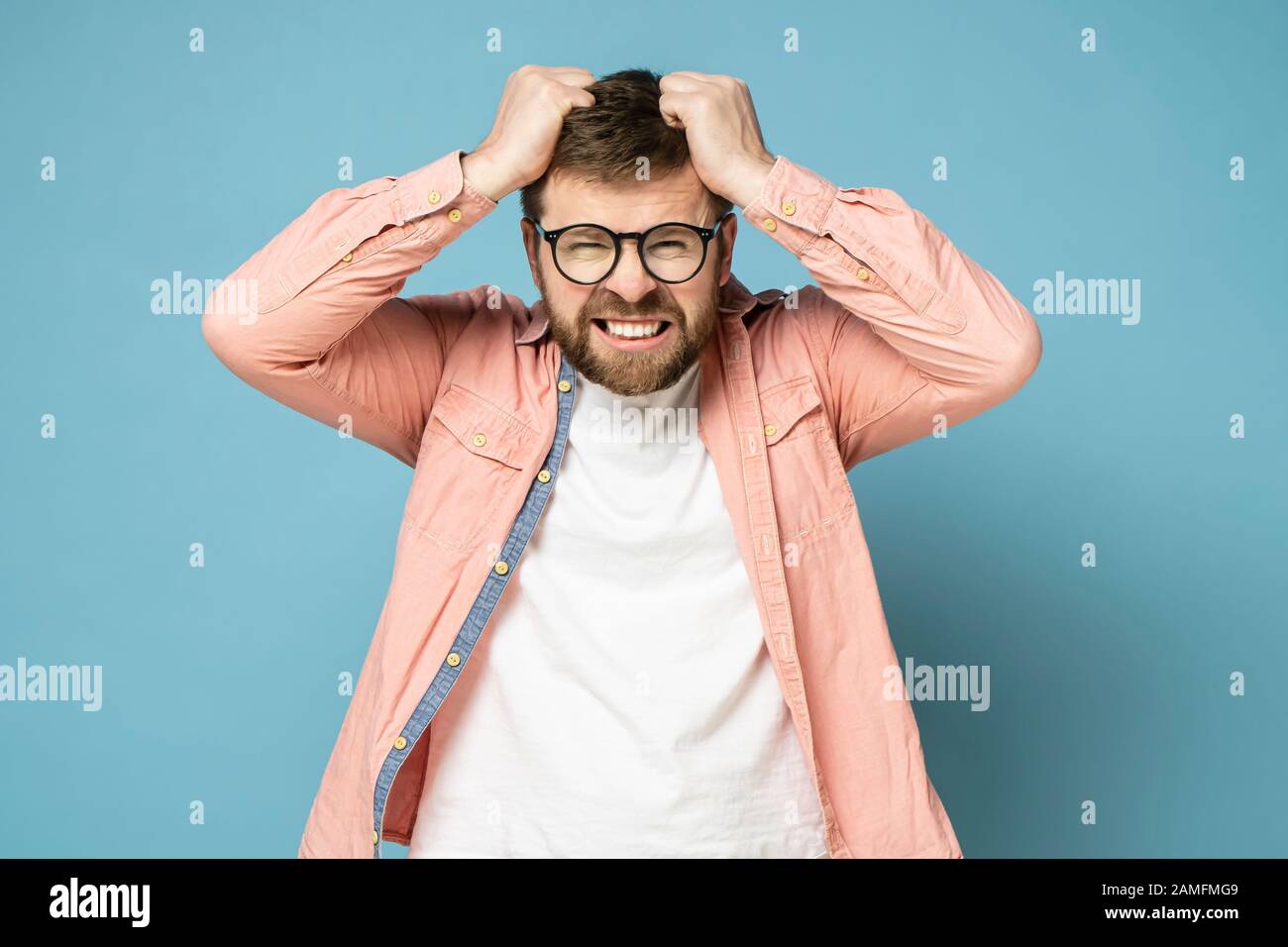 Hombre barbudo en ira y furioso, está tratando de rasgar su cabello en la cabeza y enrejar los dientes. Foto de stock