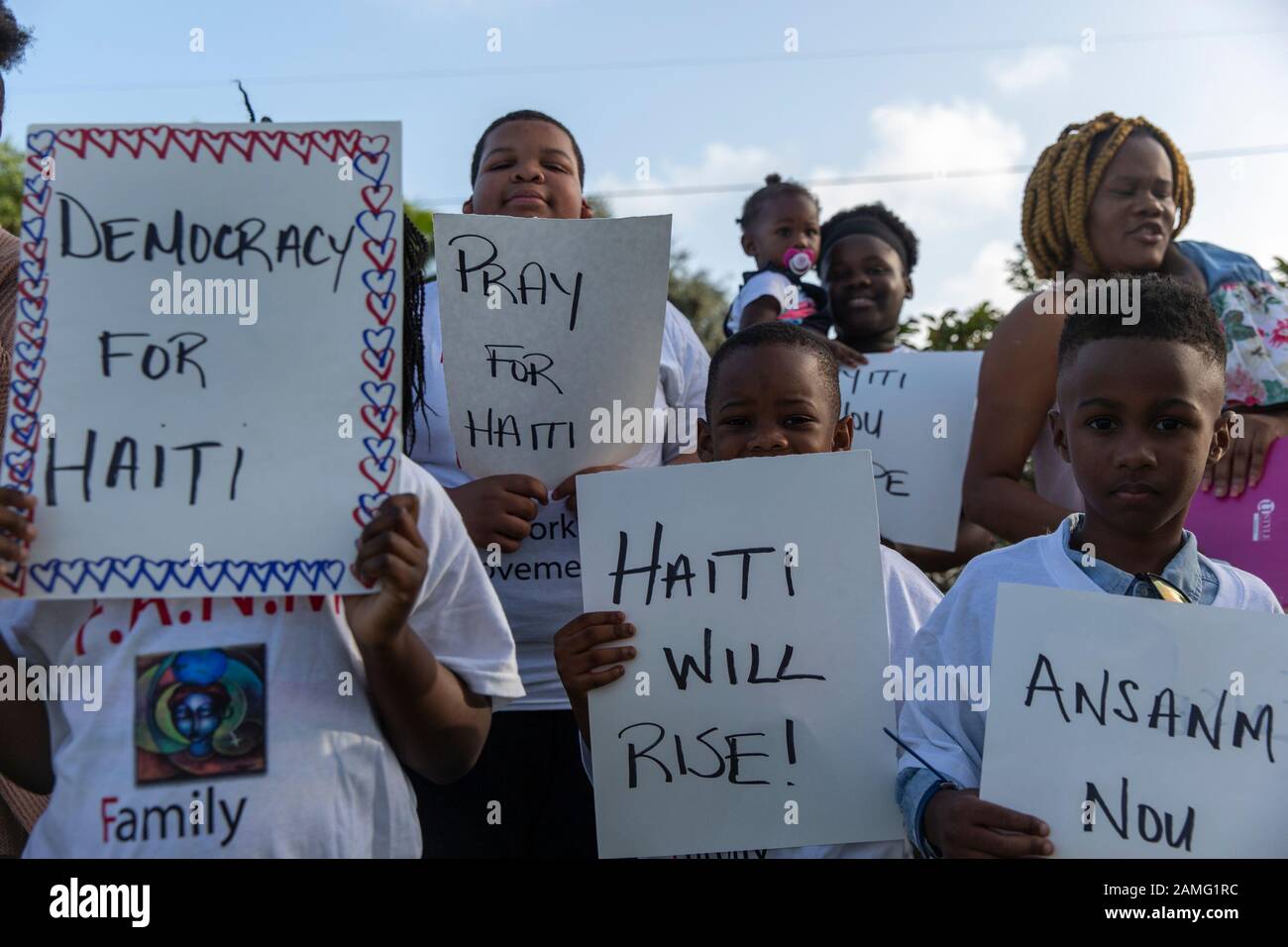 Miami, Estados Unidos. 13 de enero de 2020. Los niños celebran pancartas durante la ceremonia en el Centro Cultural Little Haiti en Miami.Haiti marcó el décimo aniversario de su mayor tragedia de terremotos con una conmemoración de baja clave que incluyó ceremonias privadas, un movimiento de sangre y un renovado llamado a la unidad de su presidente. Crédito: Sopa Images Limited/Alamy Live News Foto de stock