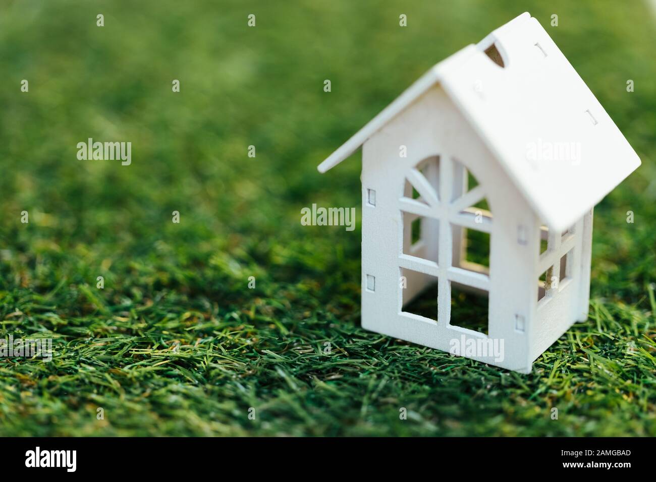Casa blanca de madera en miniatura sobre hierba verde. Inversión inmobiliaria y concepto inmobiliario financiero hipotecario. Foto de stock
