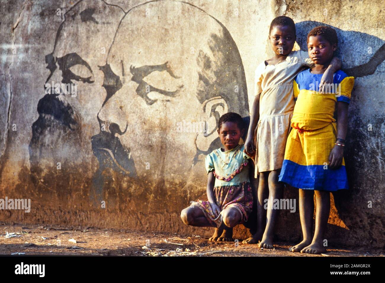 Foto vintage diapositiva de 35 mm de 1993: Niñas africanas frente a un cuadro mural que muestra a los líderes comunistas Marx y Lenin. Aldea de Quelimane en la provincia de Tete, Mozambique, África Foto de stock