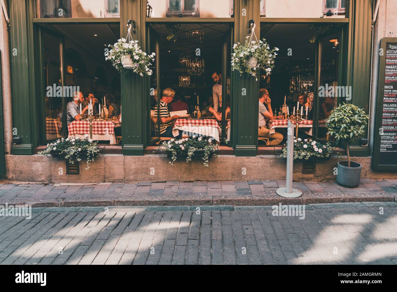 Editorial 06.20.2019 Estocolmo Suecia Gente comiendo en un restaurante con las grandes ventanas abiertas a la calle en un día caluroso de verano Foto de stock