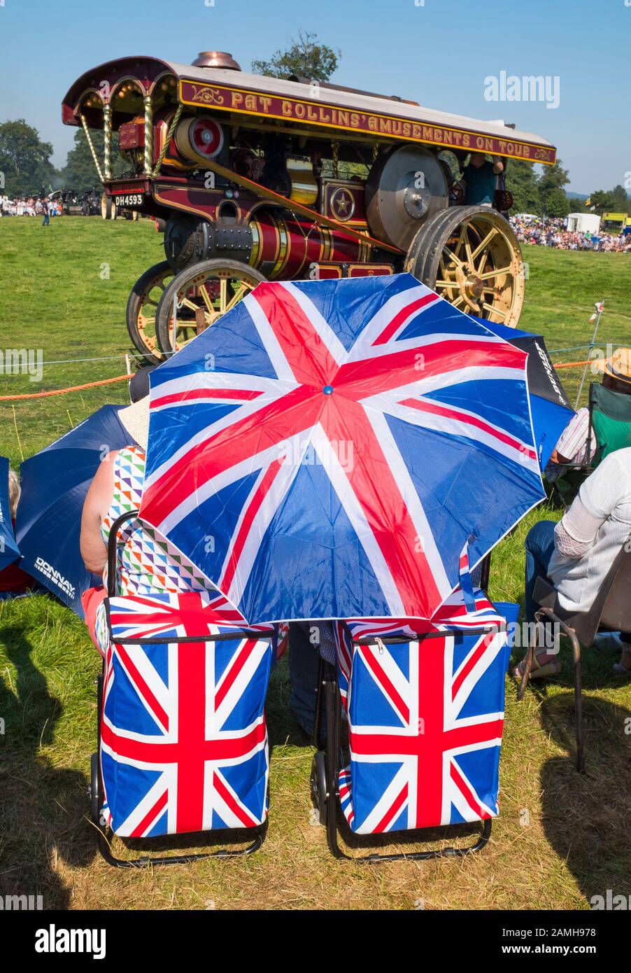 Los espectadores con un paraguas con bandera sindical ven un desfile de motores de tracción en 2019 Shrewsbury Steam Rally, Shropshire, Inglaterra, Reino Unido Foto de stock