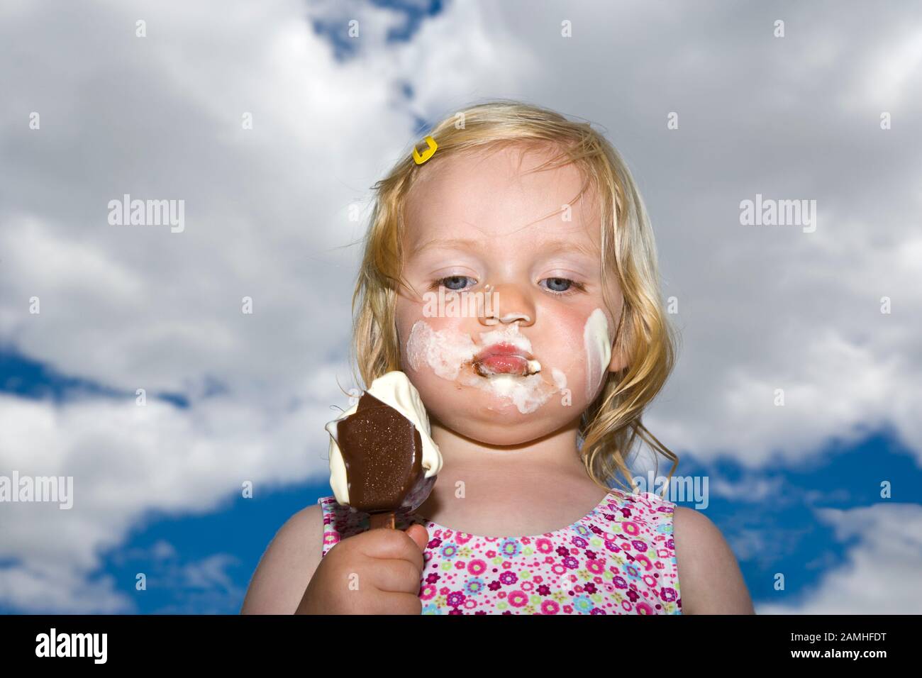 Niña comiendo helado con helado en la cara Foto de stock