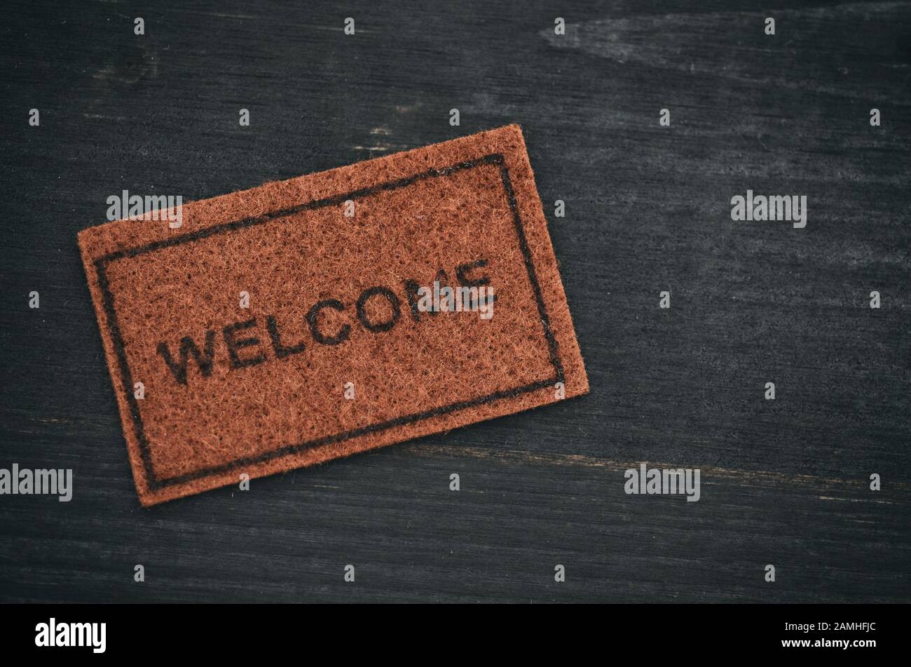 Antigua alfombra de bienvenida sobre fondo de madera negro, concepto de bienvenida, concepto de casa Foto de stock