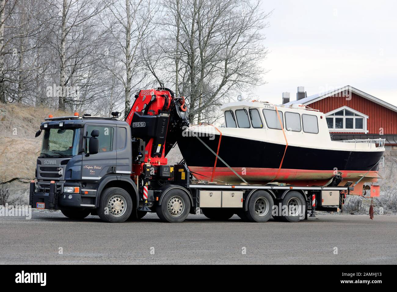 El camión de cama plana Scania P440 con grúa Fassi F990 transporta un barco de pesca. Salo, Finlandia. 11 De Enero De 2020. Foto de stock