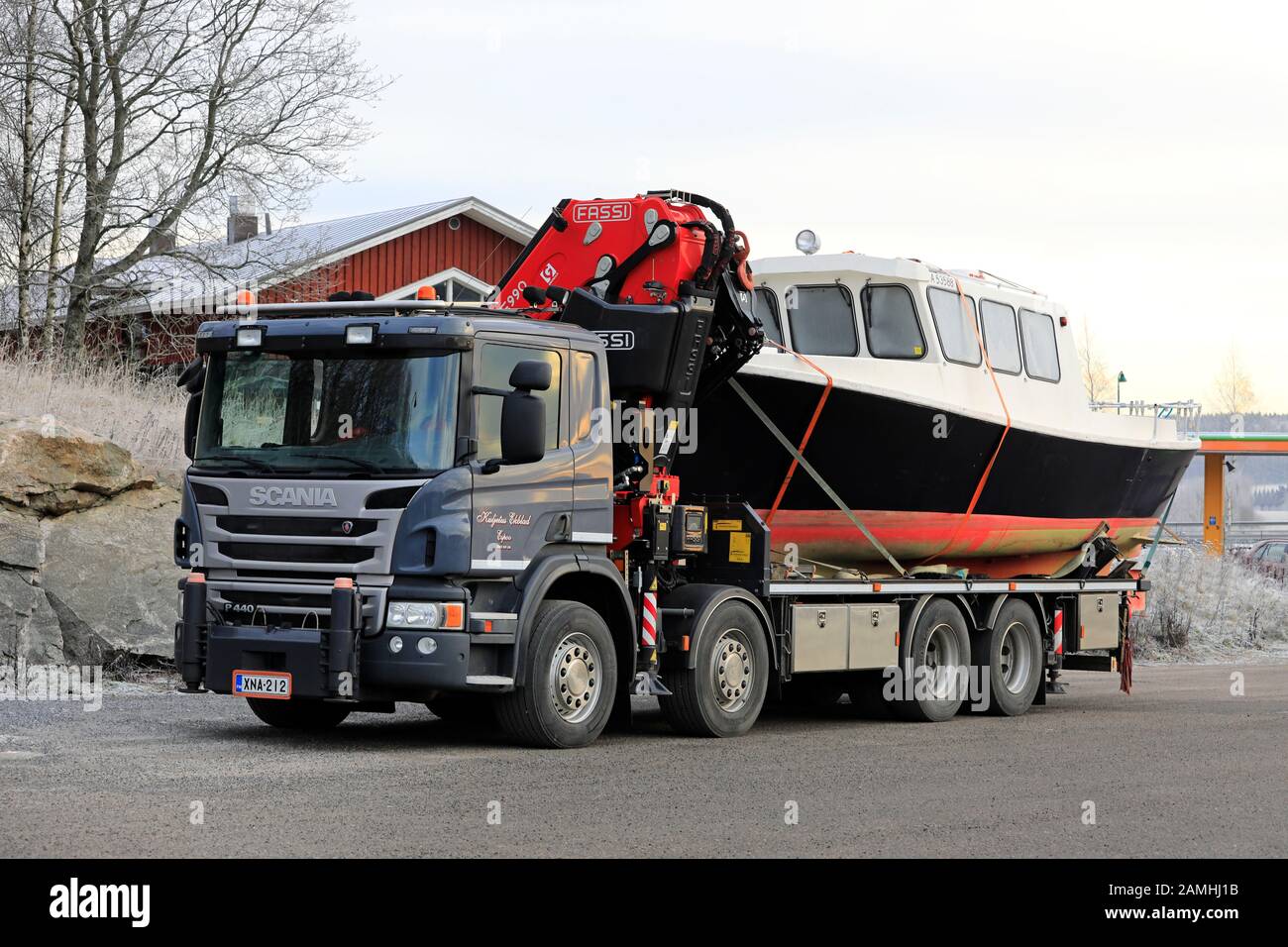 El camión de cama plana Scania P440 con grúa Fassi F990 transporta un barco de pesca. Salo, Finlandia. 11 De Enero De 2020. Foto de stock