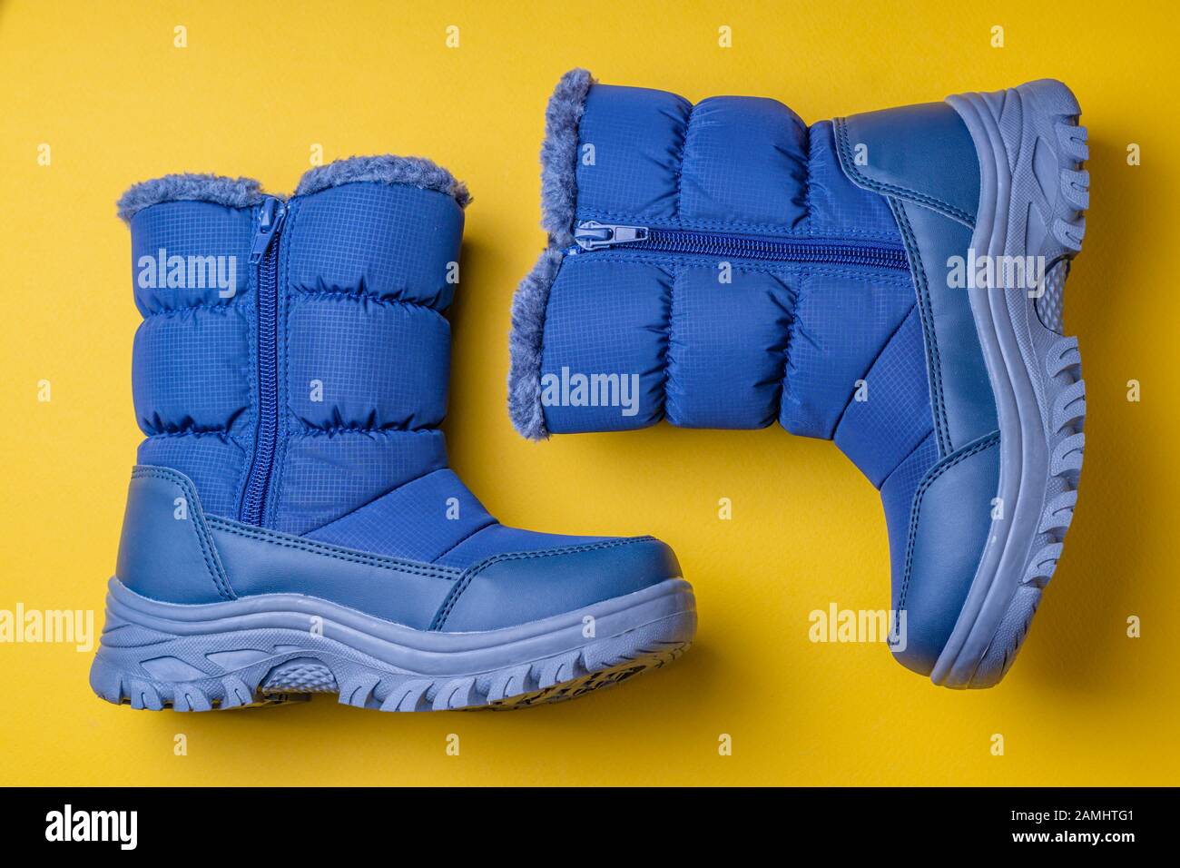 Botas de invierno impermeables en azul con suela gris sobre fondo amarillo  Fotografía de stock - Alamy