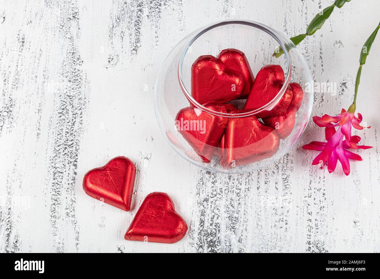 Caramelos de chocolate en forma de corazón envueltos en papel de aluminio  para el día de San Valentín. Día de San Valentín de fondo con chocolates  corazones y rojo febrero flor Fotografía