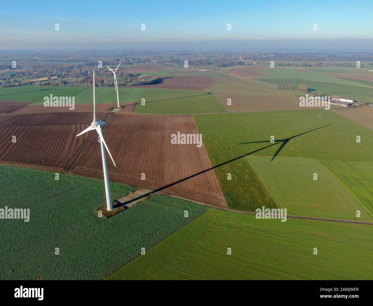 Vista aérea de los aerogeneradores en campos agrícolas durante el día azul de invierno. Producción de energía con energía limpia y renovable. Foto de stock