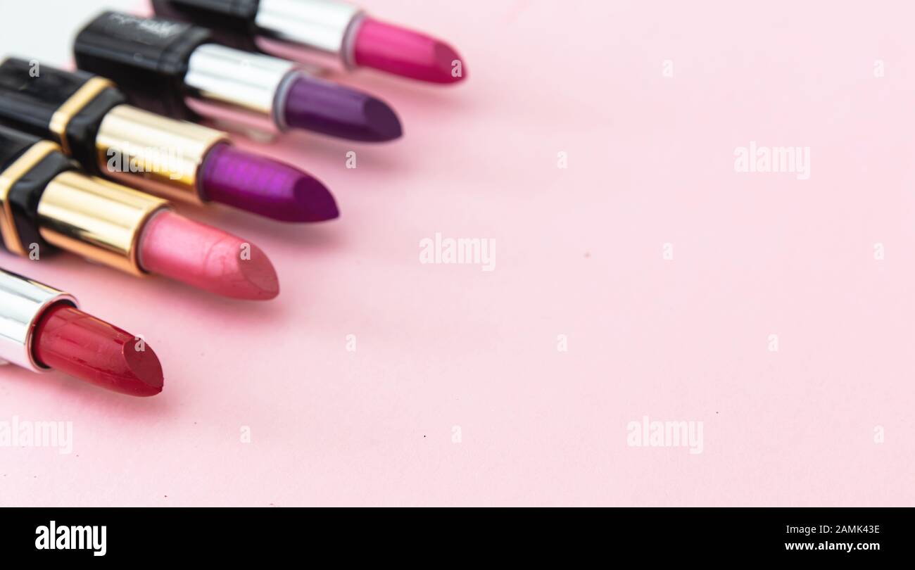 Barras de labios de colores contra fondo rosa, vista primer plano. Colores brillantes brillo de labios, cosméticos, concepto de maquillaje Foto de stock