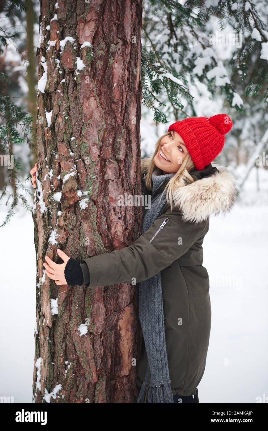 Mujeres jóvenes abrazando el árbol en el bosque de invierno Foto de stock