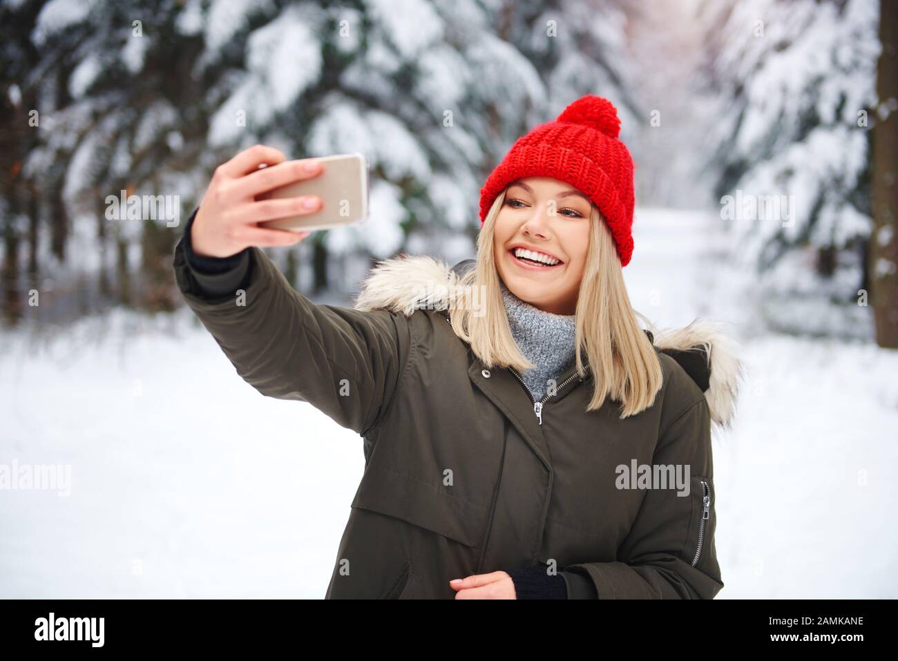 Mujer sonriente haciendo selfie en el bosque de invierno Foto de stock