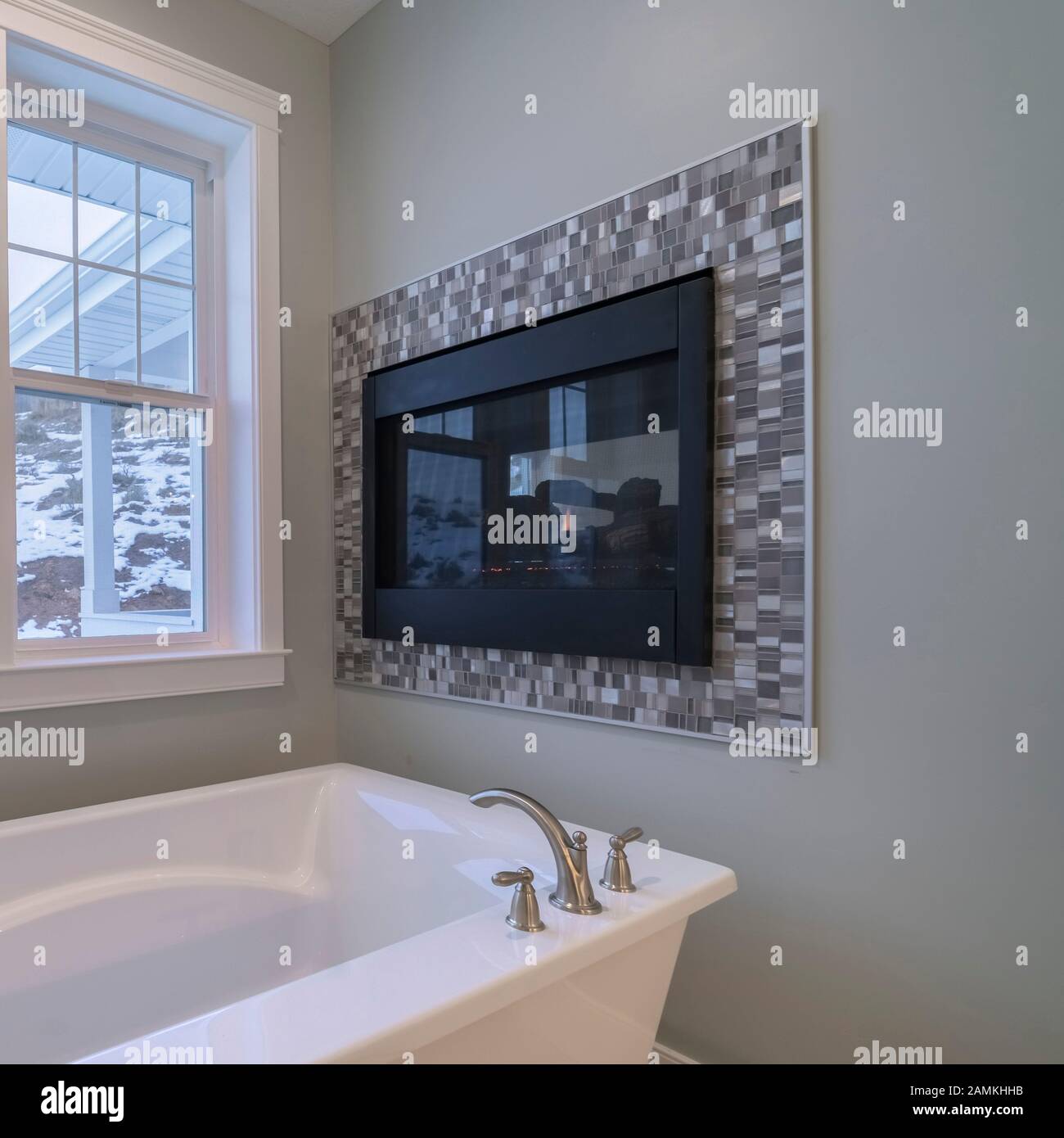 Pequeña y cuadrada bañera independiente debajo de una ventana grande  interior brillante Fotografía de stock - Alamy