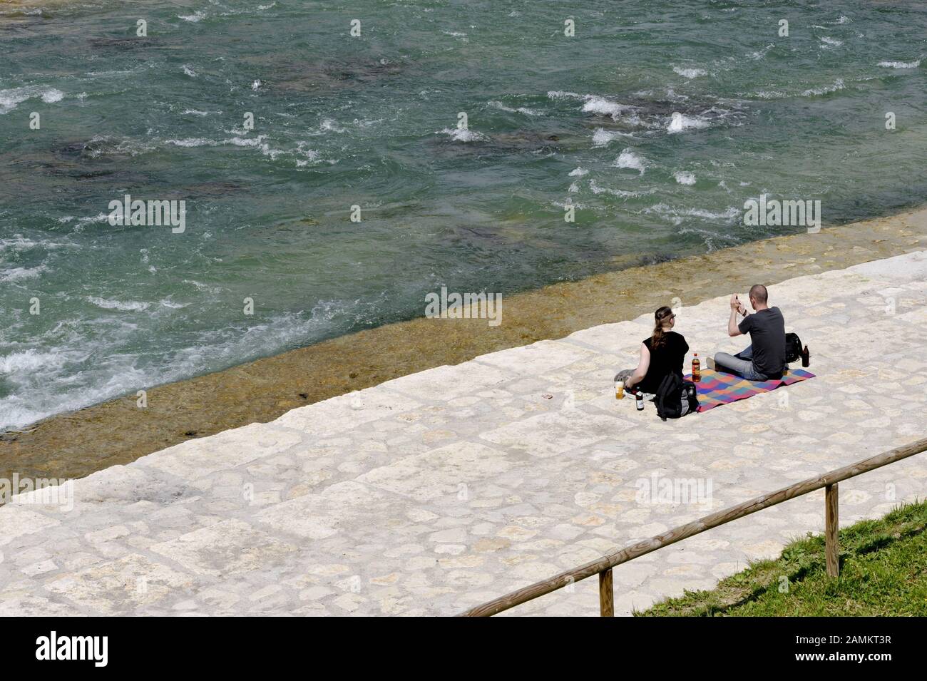 En verano, las personas que buscan relajarse se sientan a orillas del Isar cerca del Puente Reichenbach. [traducción automática] Foto de stock