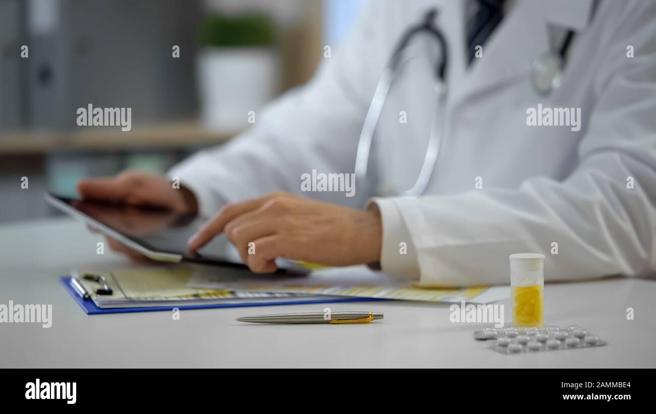 Médico jefe consultando al paciente en línea utilizando tablet, tecnologías modernas Foto de stock