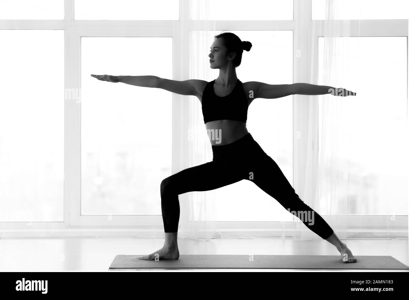 Silueta de la mujer haciendo postura de guerrero yoga Foto de stock