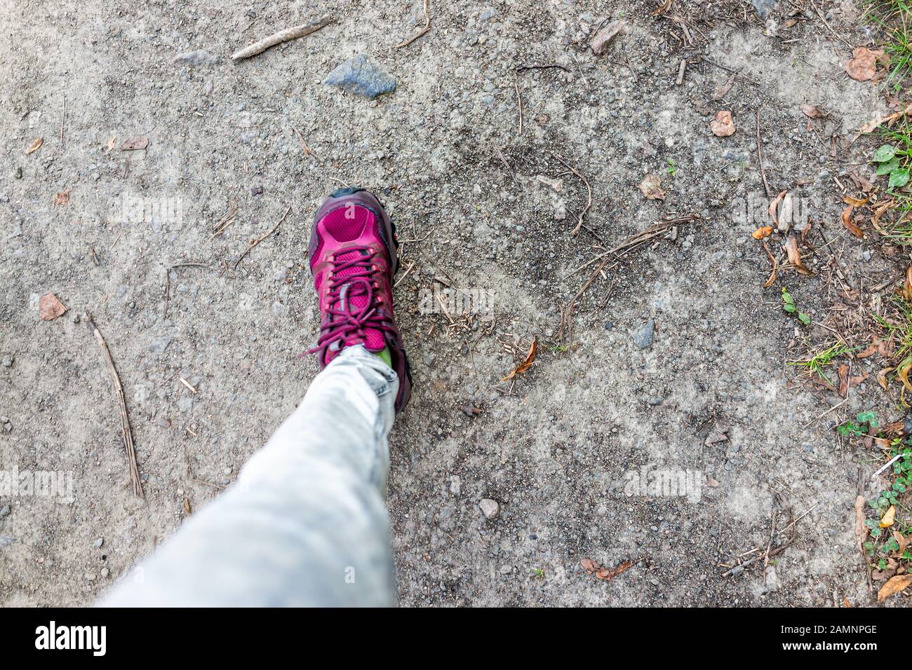 Punto de vista perspectiva personal de la pierna de la mujer caminando con un vibrante y colorido zapato rojo púrpura en la acera del suelo en el parque y jeans plano Lay top Foto de stock