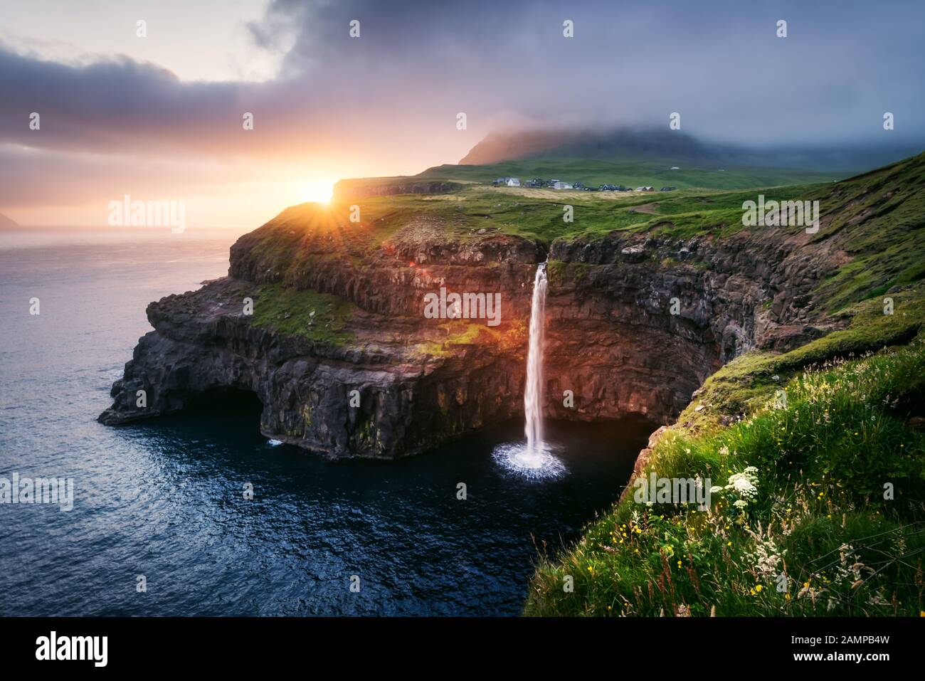 Increíble vista de la puesta de sol de la cascada Mulafossur en Gasadalur pueblo, Vagar isla de las Islas Feroe, Dinamarca. Fotografía de paisajes Foto de stock