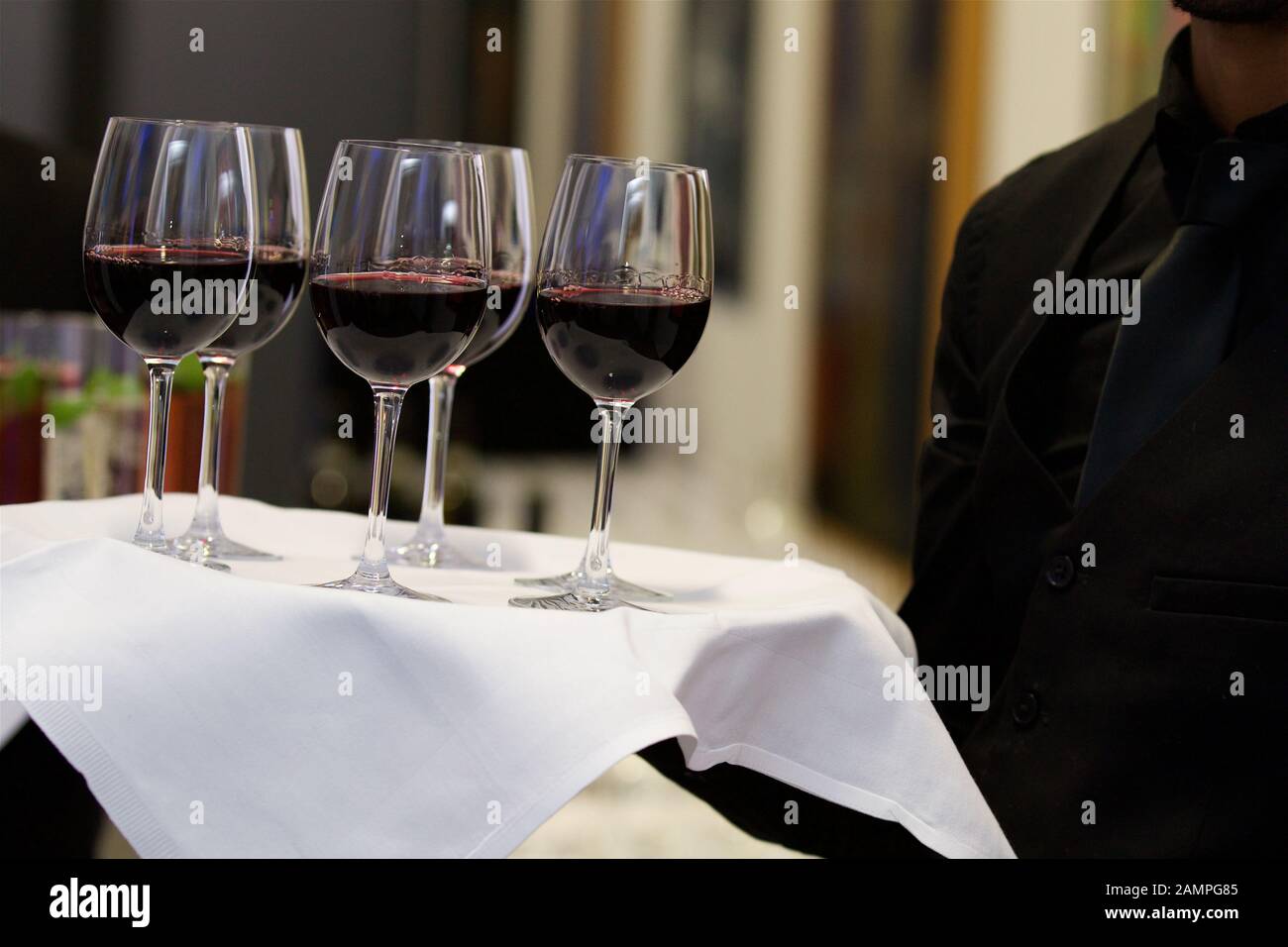 Un camarero que sirve copas de vino tinto en una bandeja. Foto de stock
