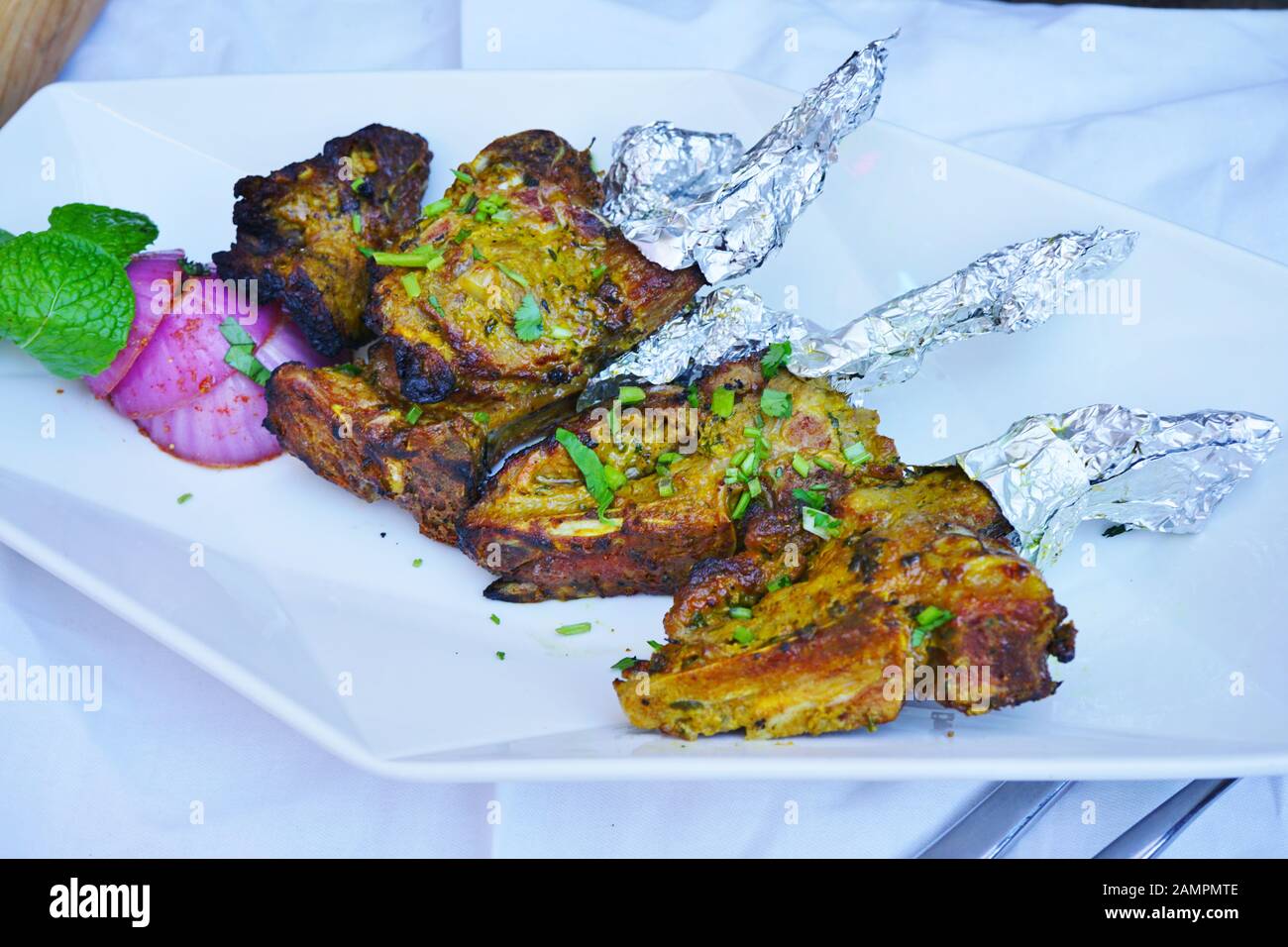 Una fuente de chuletas de cordero a la parrilla envuelta en papel de  aluminio en un restaurante indio Fotografía de stock - Alamy