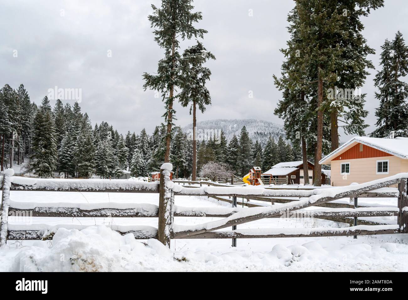 Una escena invernal de una casa de campo y un granero cubiertos de nieve en las montañas del norte de Idaho, EE.UU Foto de stock
