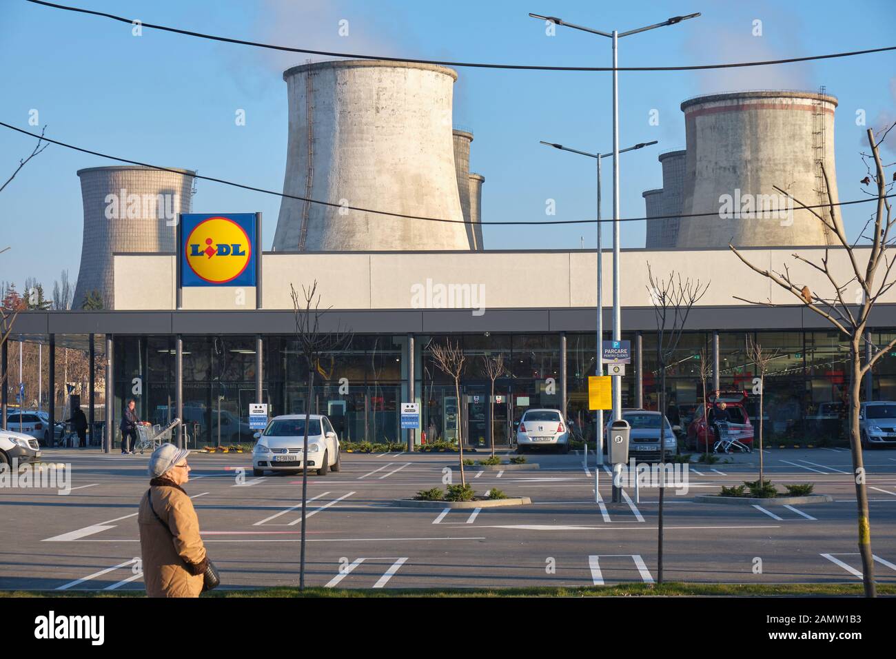 Bucarest, Rumanía - 8 de enero de 2020: Almacén de alimentos Lidl y torres de refrigeración de una central de carbón (CET Sud) en la parte trasera. Contraste entre comida saludable sh Foto de stock