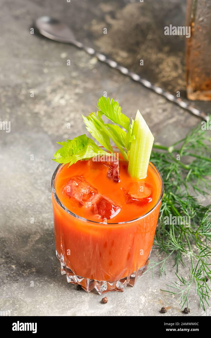Cóctel de jugo de tomate Bloody mary e ingredientes tomate, lima, apio, perejil. Bebidas en elegantes vasos de cristal sobre un fondo gris. Vertical Fotografía de stock - Alamy