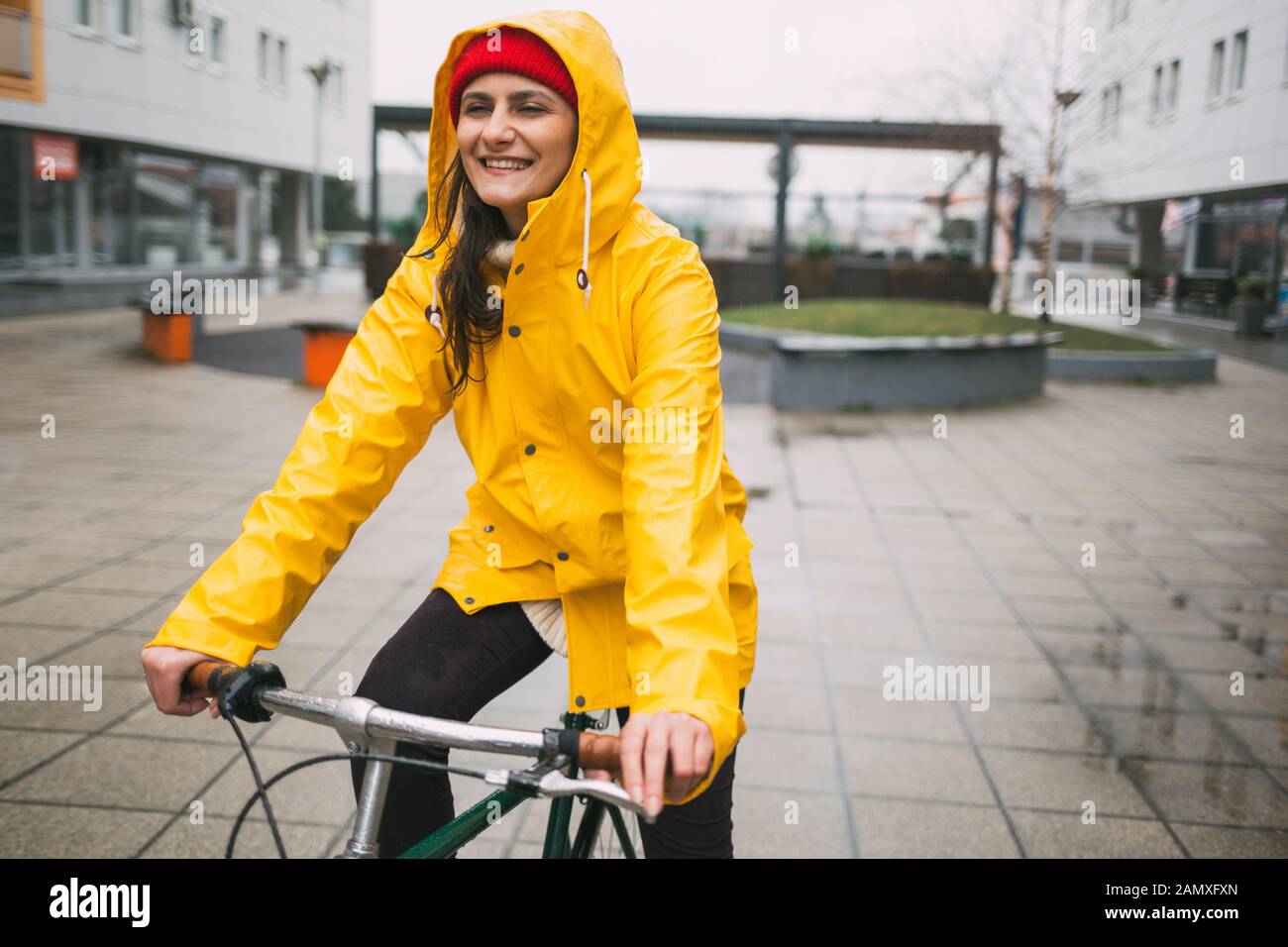bala este Sentido táctil Mujer sonriente el ciclismo en la lluvia. Chica en bicicleta impermeable  amarillo Fotografía de stock - Alamy