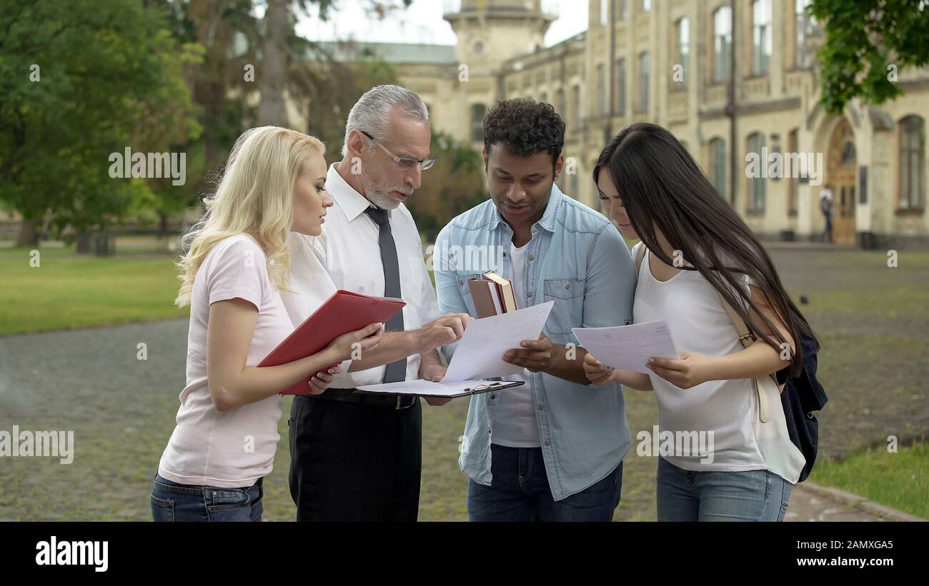 Profesor de alto nivel discutiendo los resultados de las pruebas con el grupo de estudiantes, cooperación Foto de stock