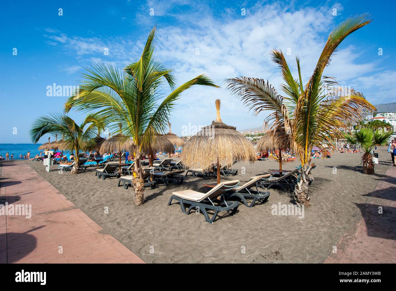 ISLAS Canarias TENERIFE, ESPAÑA - 26 Dic, 2019: Los turistas están tumbados y relajándose entre palmeras y reposeras en la playa llamada playa de Torviscas. Foto de stock