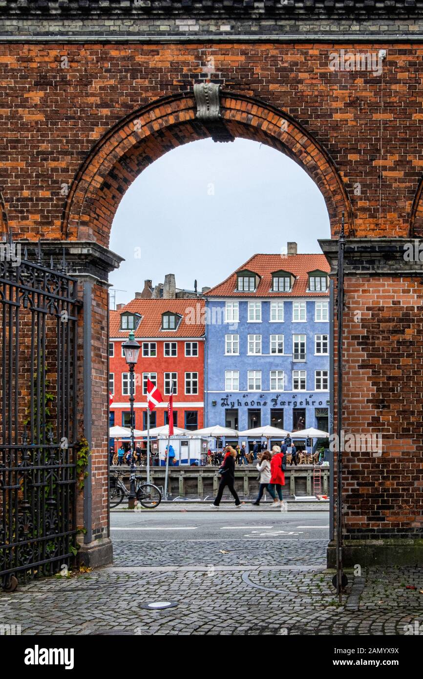 Vista de coloridos edificios Palacio Charlottenborg Nyhaven mediante arco de entrada de ladrillo en Copehagen, Dinamarca Foto de stock