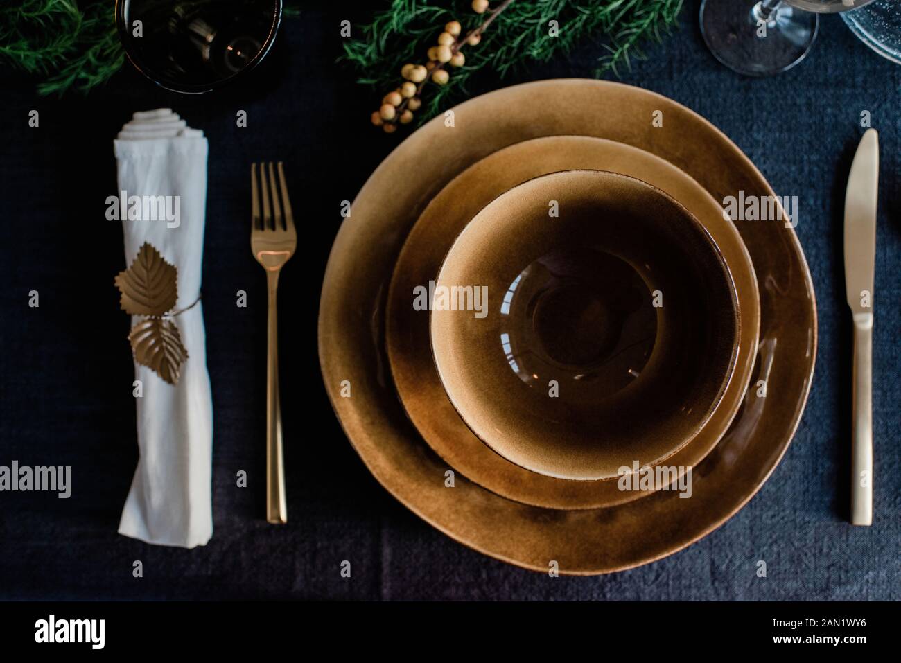 platos y cuencos dorados con cubiertos dorados en una mesa de cena decorada Foto de stock