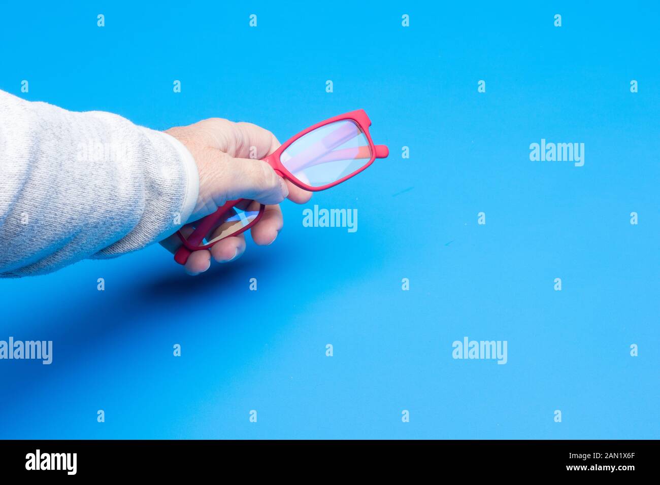 Las gafas en la mano de un adulto; gafas y lentillas coloreadas, moderno,  con cristales corregido para dar una visión correcta y para ver de lejos y  de cerca Fotografía de stock -