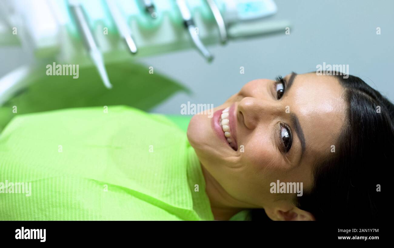 Señora mira a la cámara con sonrisa blanco-nieve, la satisfacción con el tratamiento de dientes Foto de stock