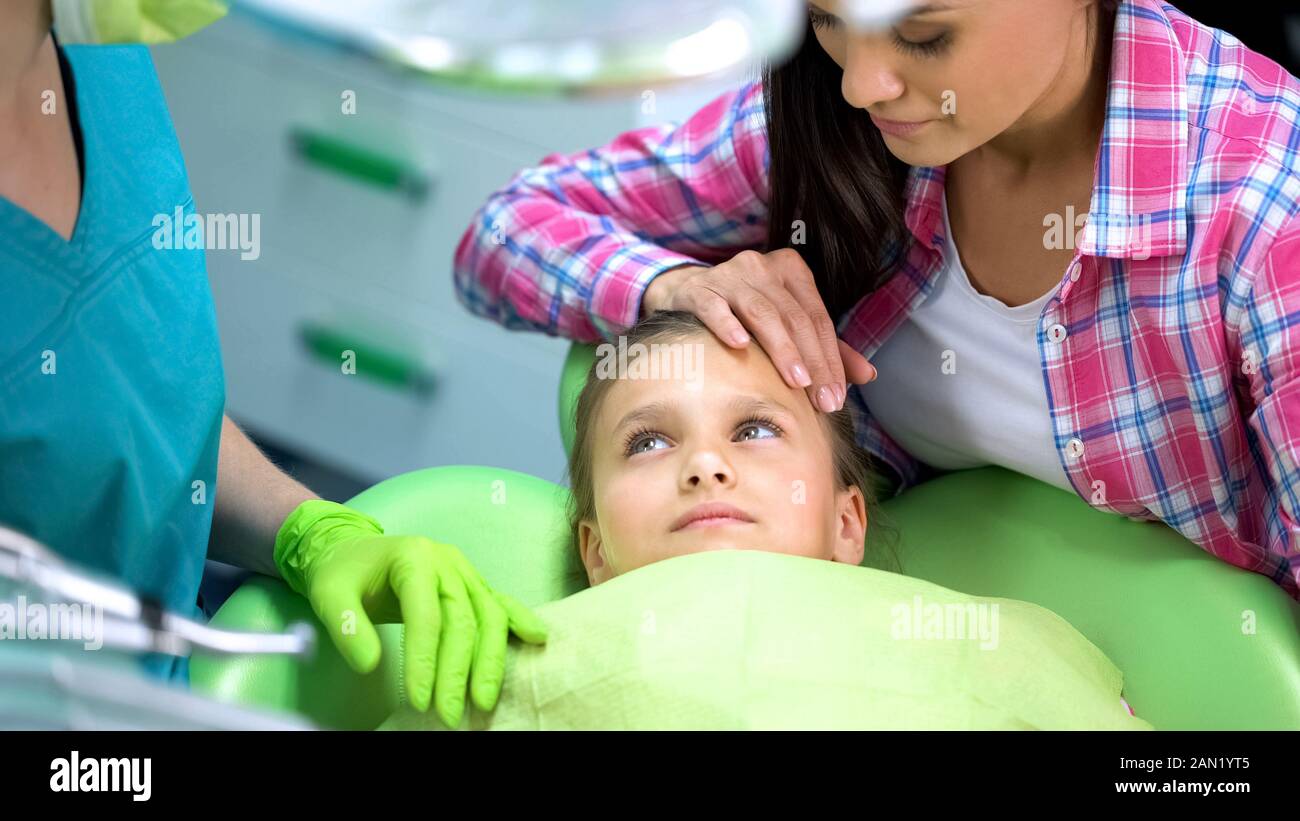 Niños preescolares mirando al dentista, madre calmantes antes del