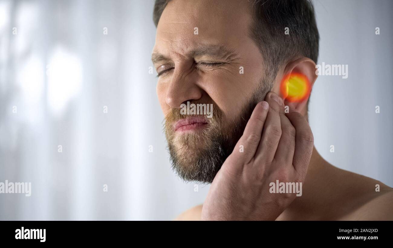 El hombre sufre de dolor de oído, otitis, problemas de audición, spot indica dolor, closeup Foto de stock