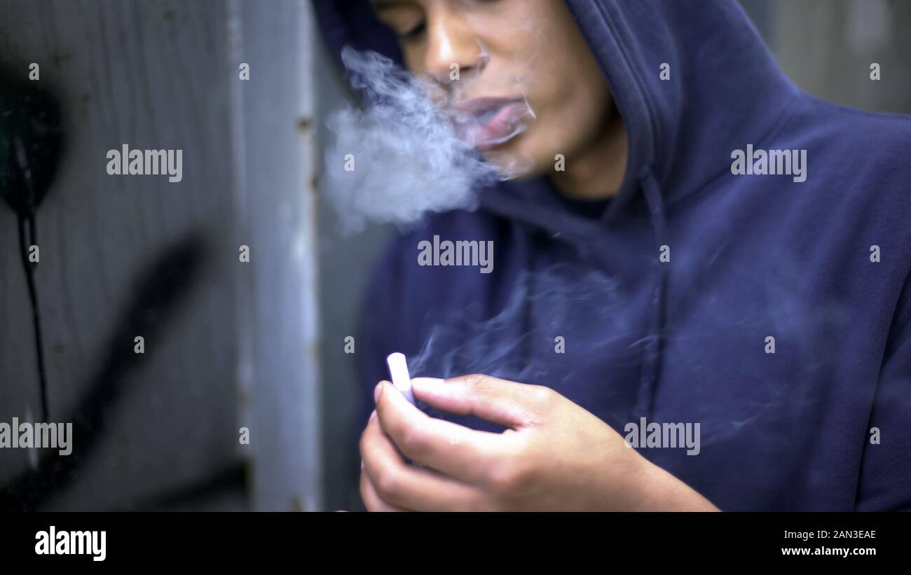 Pensativo chico adolescente fumando nerviosamente, planificar su futuro, cruel realidad Foto de stock