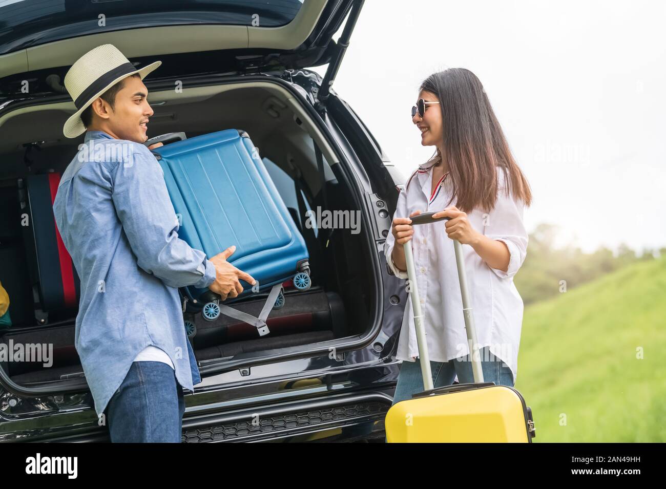Hombre Mujer Asiática ayudando a levantar la maleta del coche durante un  viaje de fin de semana largo. Pareja de viaje en vacaciones con amarillo el  equipaje. Gente la vida Fotografía de