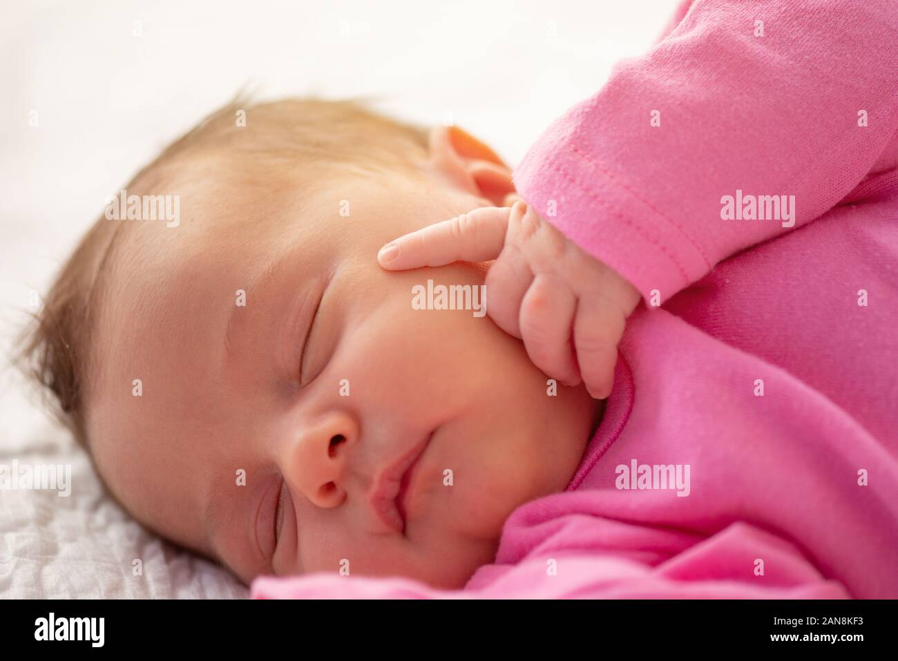 Poco lindo recién nacido dormía con su dedo en la cara Foto de stock