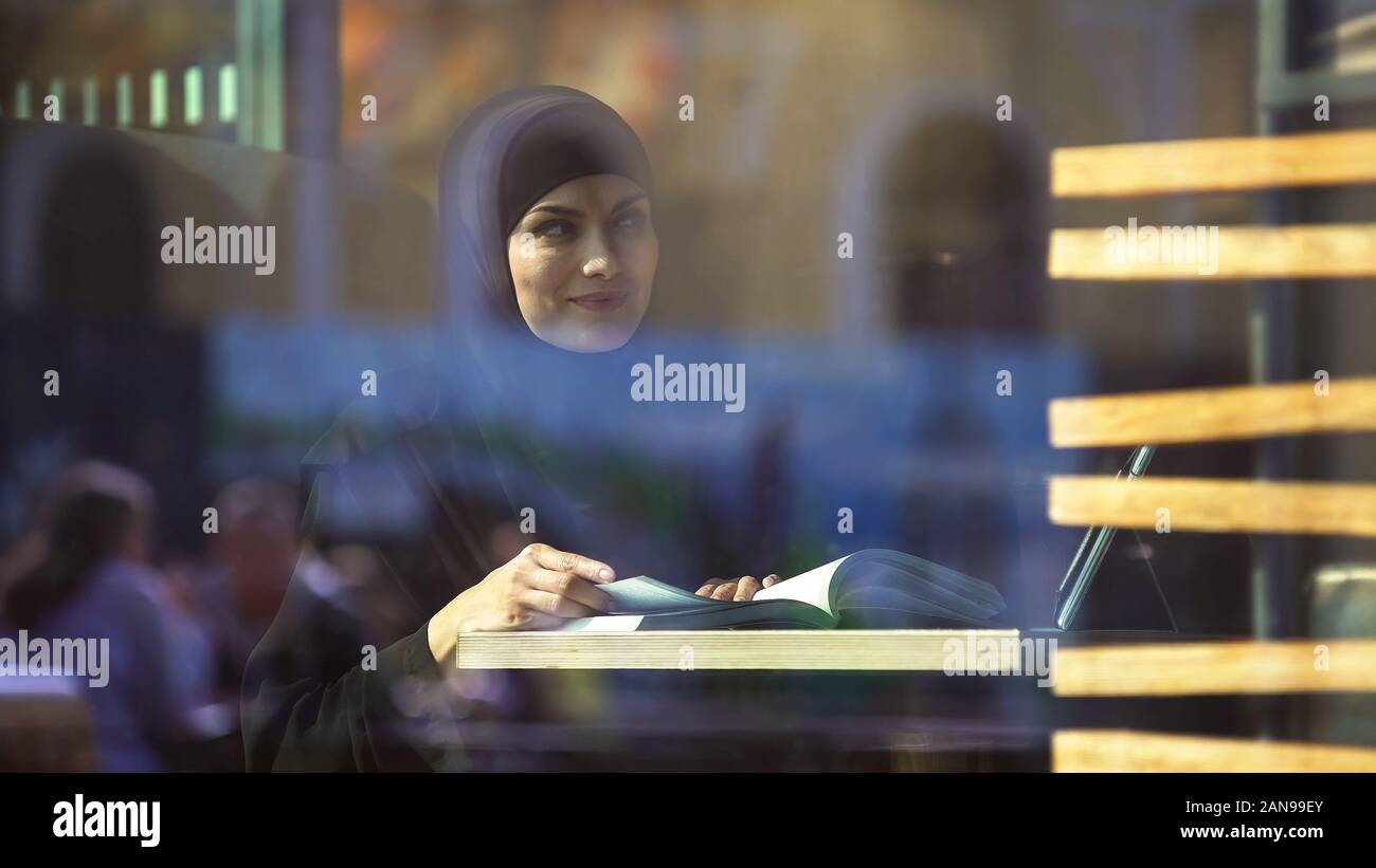 Atractiva estudiante femenina en ropa tradicional árabe de libro de lectura en el café Foto de stock