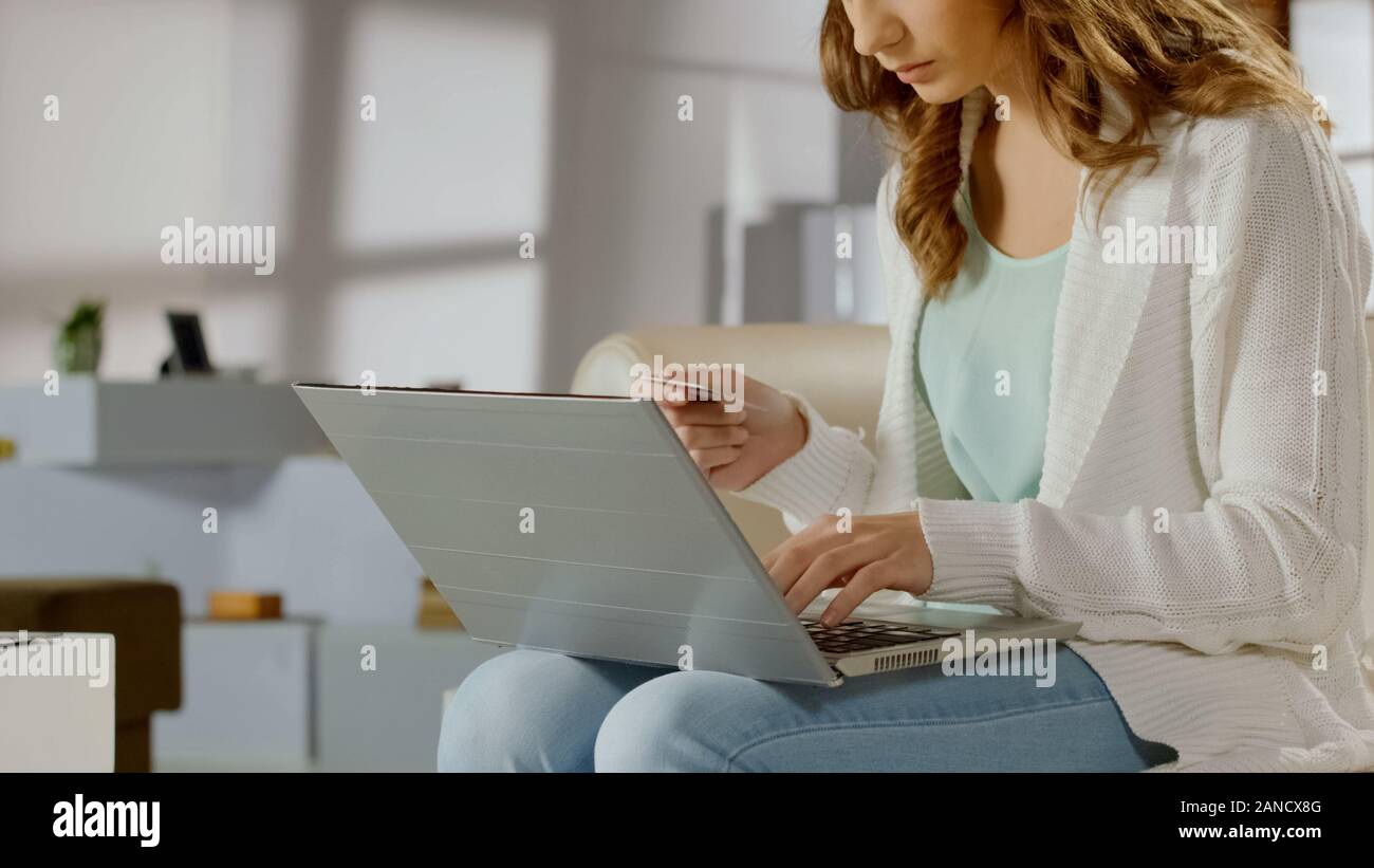 Mujer joven pagar en línea con tarjeta bancaria mediante portátil, transacción financiera Foto de stock
