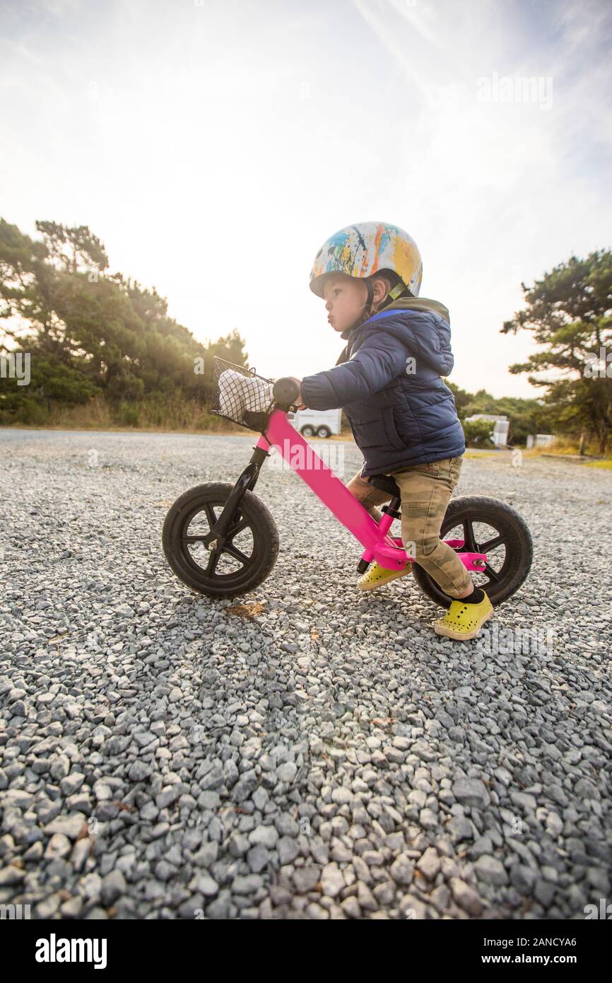 Vista lateral de una niña de un año en bicicleta rosa. Foto de stock
