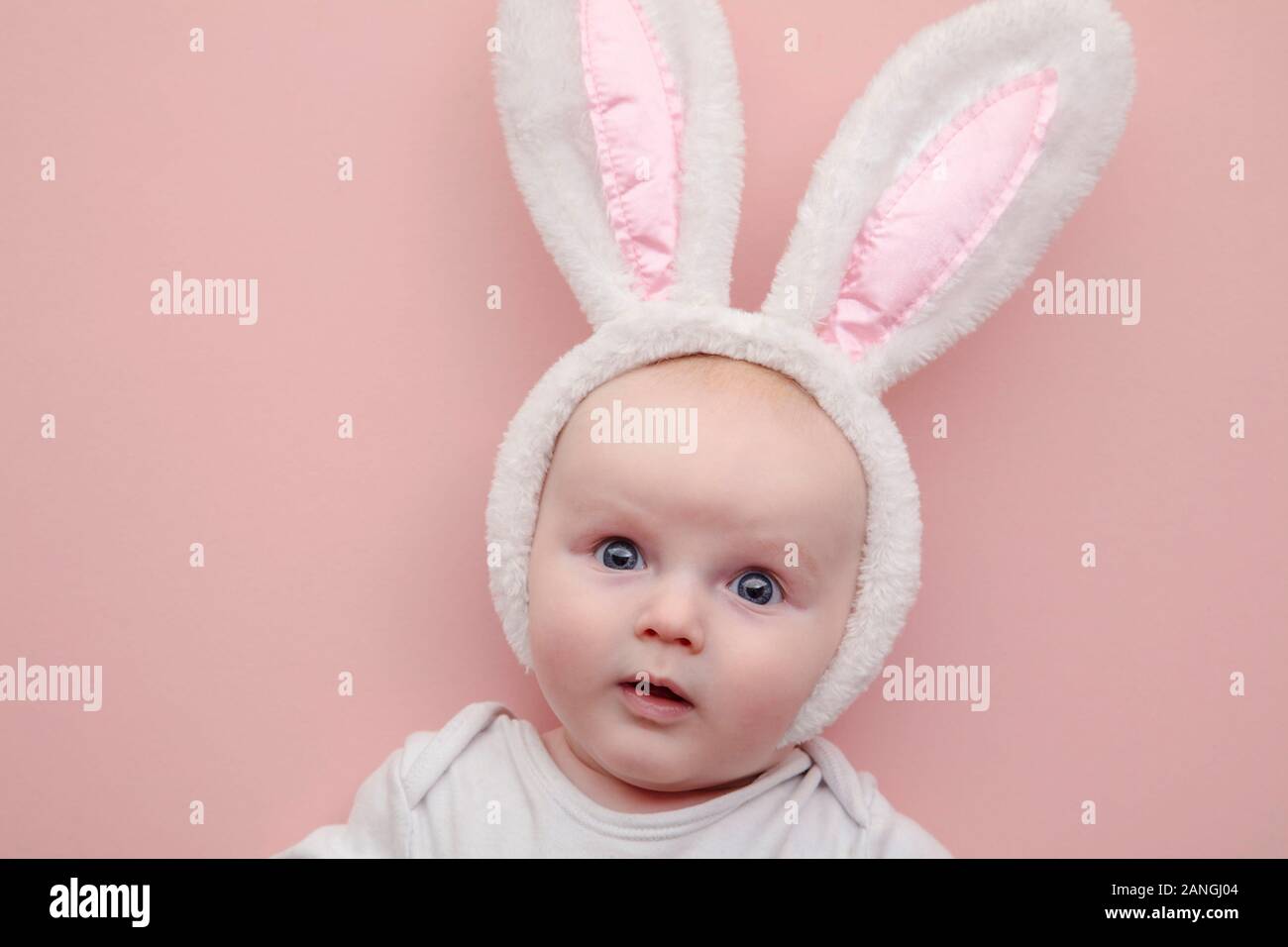 Cute little baby vistiendo Easter Bunny orejas de conejo sobre un fondo de color rosa Foto de stock