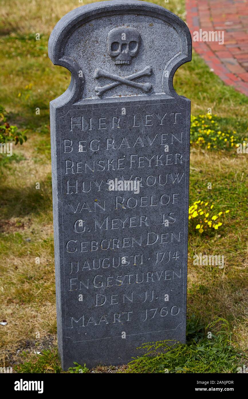 Lápida gris con cráneo y crossbones y epitafio escrito en lengua holandesa Foto de stock