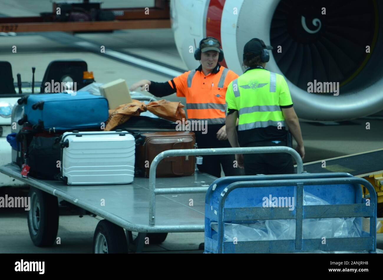 los gestores de equipaje del aeropuerto cargan equipaje y carga en el avión de pasajeros Foto de stock