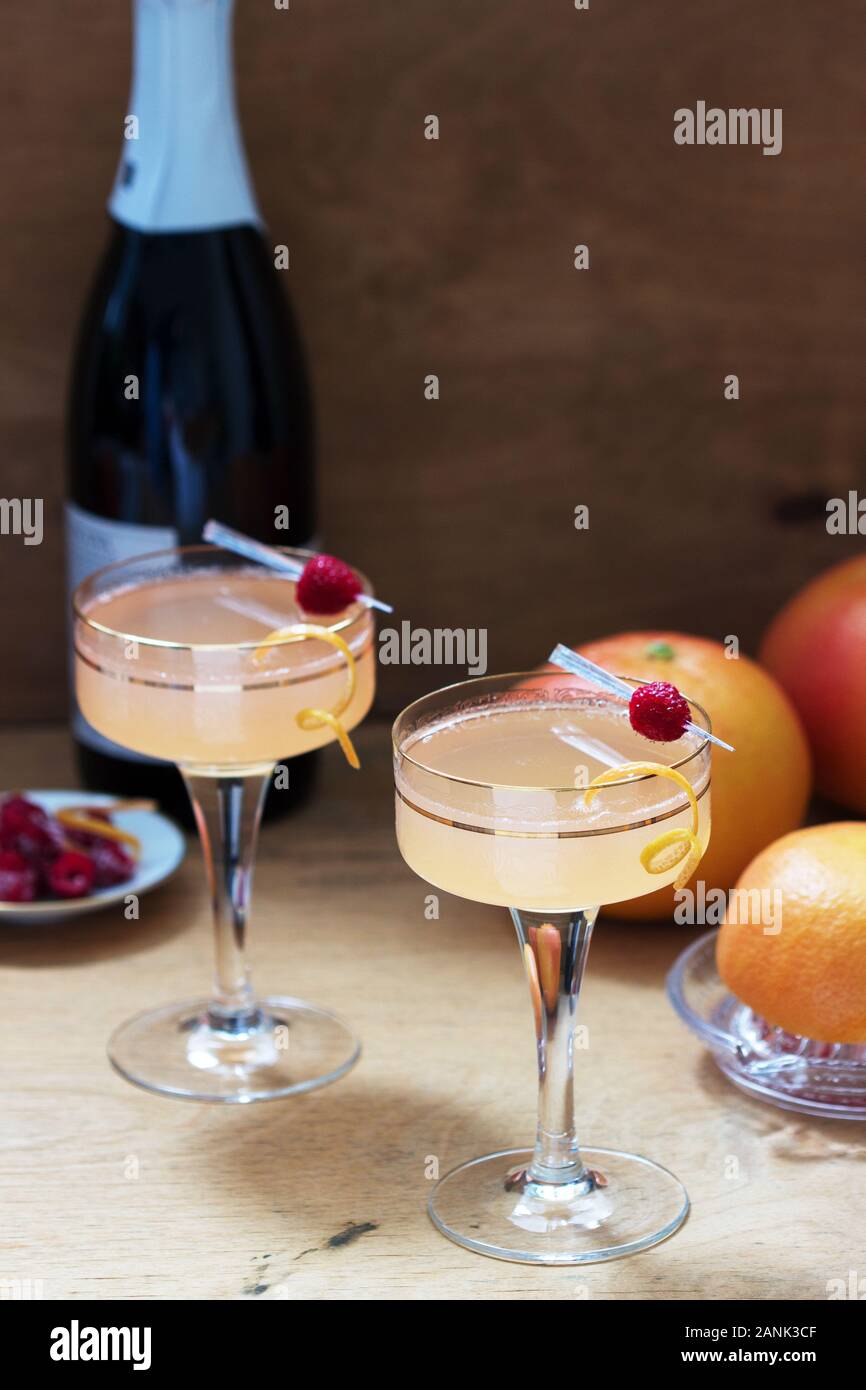 Cóctel de champán con jugo de toronja, aderezado con zest y frambuesas. Estilo rústico. Foto de stock