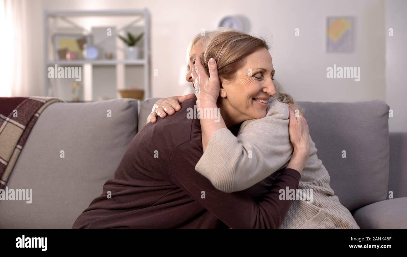 Dos mujeres maduras abrazando sentado en un sofá en el salón, hermanas  amor, familia Fotografía de stock - Alamy